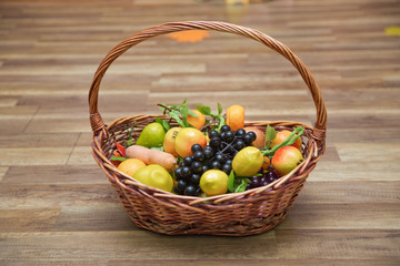 Apples, plums and a mountain ash in a basket, top view. Table-still life. Fresh juicy citrus fruits in a basket on a wooden background . Basket and fresh fruits on wooden table .