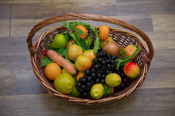 Apples, plums and a mountain ash in a basket, top view. Table-still life. Fresh juicy citrus fruits in a basket on a wooden background . Basket and fresh fruits on wooden table .