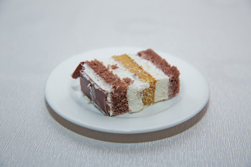 Close-up shot. Free space for text.Slice of chocolate cake white cream on plate. Chocolate cake with whipped cream . A slice of cake in a white plate on a white wooden table with a spoon.