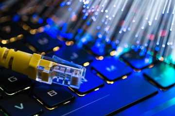 Yellow internet switch on rgb gaming laptop keyboard, glowing optical fibres in the background.