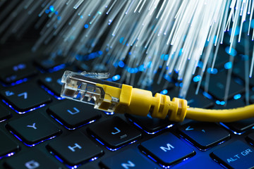 Yellow internet switch on rgb gaming laptop keyboard, glowing optical fibres in the background.