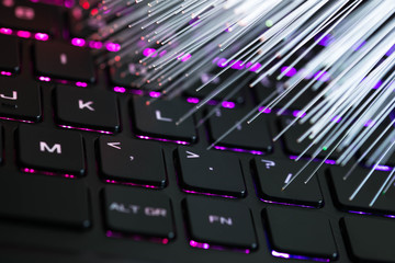 Optical fibres over colorful rgb gaming laptop keyboard close up shot, copy space.