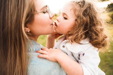 Blonde mother with two cute daughters are walking and having fun outdoors. Stylish, casual clothes.