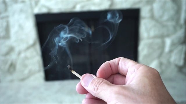 person lighting match for fireplace