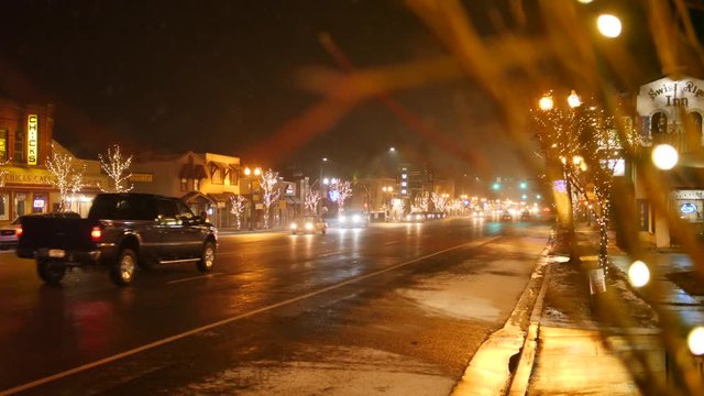 A cute small town main street decorated in Christmas lights with cars