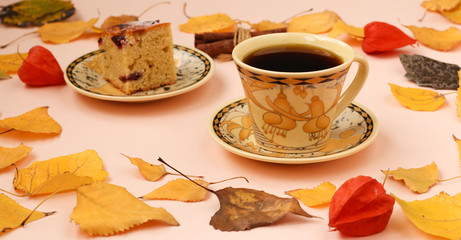 Autumn composition with cup of coffee, piece of cake and cinnamon sticks frame made of autumn leaves, horizontal orientation, copy space