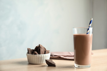 Glass of tasty chocolate milk on wooden table, space for text. Dairy drink