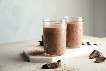 Jars with tasty chocolate milk on table. Dairy drink