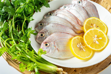 A red plate with fresh red mullet and spices on a white background