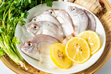 A red plate with fresh red mullet and spices on a white background