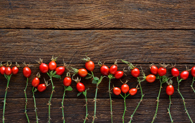 rosehip branches with red dog rose fruits on a brown wooden table