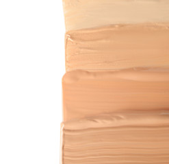 Samples of different foundation shades on white background, top view