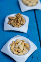 Peanuts in small white saucers on a wooden blue background.