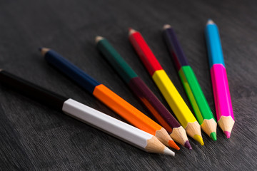 Colored pencils isolated on dark wooden background