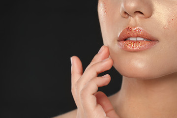 Obraz premium Beautiful young woman with glitter makeup on black background, closeup view. Space for text
