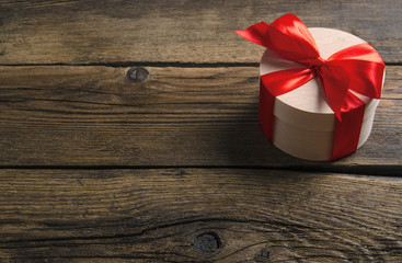 Box with red ribbon bow gift on wooden background
