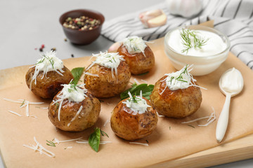 Obraz na płótnie Canvas Delicious baked potato with sour cream on wooden board