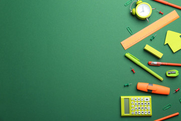 Bright school stationery on green background, flat lay. Space for text