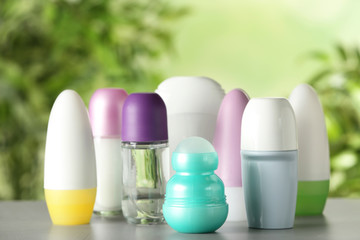 Different deodorants on white wooden table against blurred background
