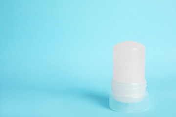 Natural crystal alum stick deodorant on light blue background, space for text