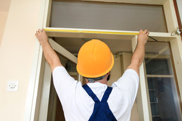 Construction worker and handyman is working on renovation of apartment. Builder is measuring of...
