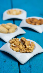 Food,taste and snack concept: walnuts in small white saucers on a wooden blue background.