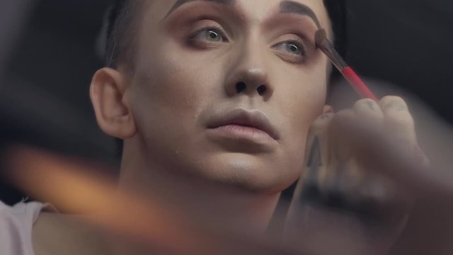 A travesty artist(transvestite) does makeup in the color dressing room before performing at a nightclub