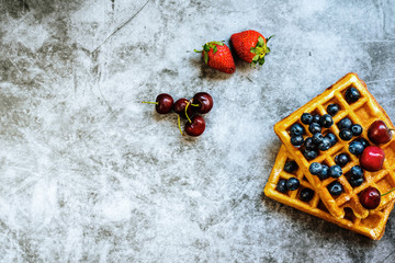 Clean background with a lot of negative space for healthy food, with red fruits and waffle.