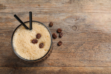 Glass of tasty refreshing cocktail with coffee beans on wooden background, top view. Space for text