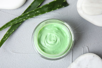 Professional face mask with spa stones and aloe on light gray table, flat lay