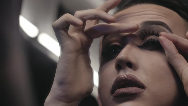 A travesty artist(transvestite) does makeup in the color dressing room before performing at a nightclub