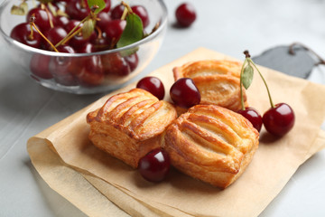 Fresh delicious puff pastry with sweet cherries served on light table
