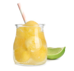 Glass jar of melon ball cocktail and lime on white background