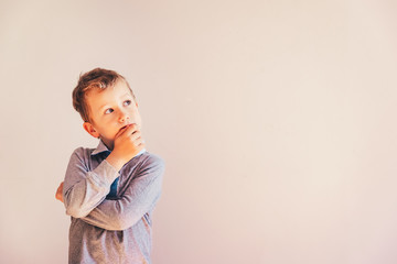 Fototapeta na wymiar 5 year old boy with very expressive thoughtful gesture, on white background with copy space area.
