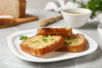 Slices of toasted bread with garlic and herb on light grey marble table, closeup