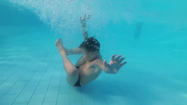 Baby in the Pool Underwater in the Form of an Embryo. Slow motion