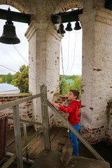 Obraz na płótnie Canvas Young boy rings the bells in the old church bell tower