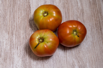Several ecological tomatoes on a wooden table 