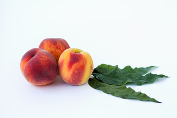 fresh peaches with green leaves isolated on white background