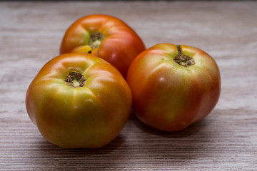Several ecological tomatoes on a wooden table 
