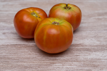 Several ecological tomatoes on a wooden table 