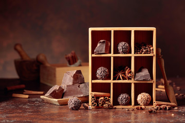 Chocolate truffles with broken pieces of chocolate and spices in wooden box.