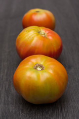 Several ecological tomatoes on a wooden table 
