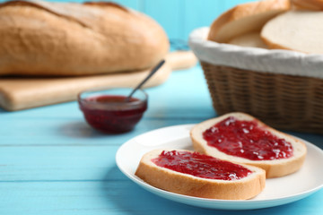 Slices of tasty fresh bread with jam on light blue wooden table