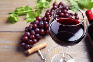 Fresh ripe juicy grapes and glass of wine on wooden table, closeup
