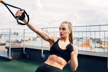 Woman doing push ups with fitness strap outdoors