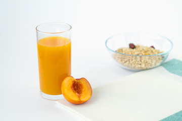 glass of peach juice and fresh fruits with cornflakes on white background