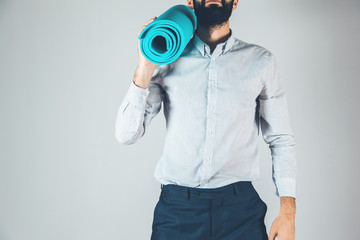 Young business man holding a yoga mat