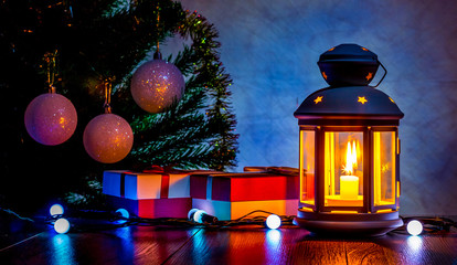 Christmas gifts under the Christmas tree in the light of a lantern with a candle at night. New Year and Christmas card_ © Volodymyr