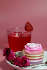 Multilayer sweet coconut fruit jelly with beverage, strawberry and red roses on white plate and pink background and space for write wording for happiness moment. Unhealthy dessert high sugar and fat. 